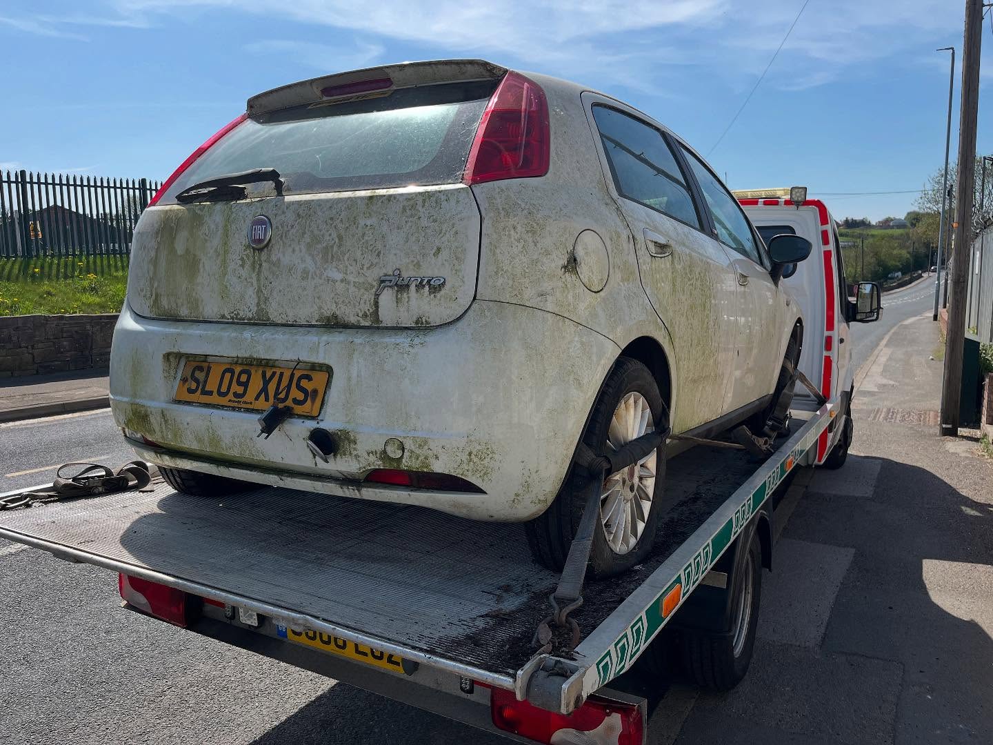 Silver Fiat Punto loaded on the back of a Leeds Scrap Cars recovery truck at a roadside collection