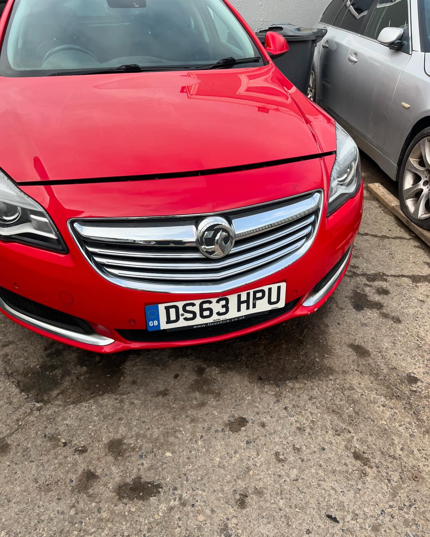 Red Vauxhall Insignia parked next to a silver car on the tarmac of the Leeds Scrap Cars yard in Armley